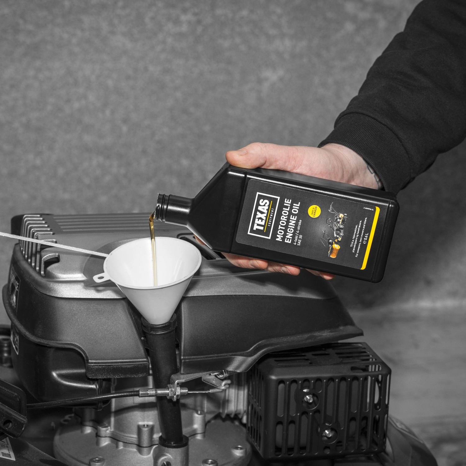 Texas Motoröl SAE30 0,6l wird in einen Rasenmäher eingefüllt.