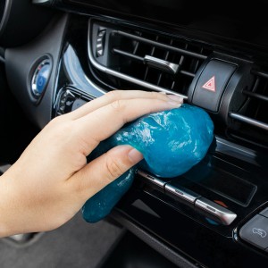 Hand nutzt blaues OKCars Auto-Reinigungsgel zur Säuberung eines Auto-Lüftungsschlitzes.