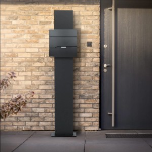 Moderner ML-Design Standbriefkasten in Anthrazit mit Zeitungsfach und Standfuß vor einer Hauswand.