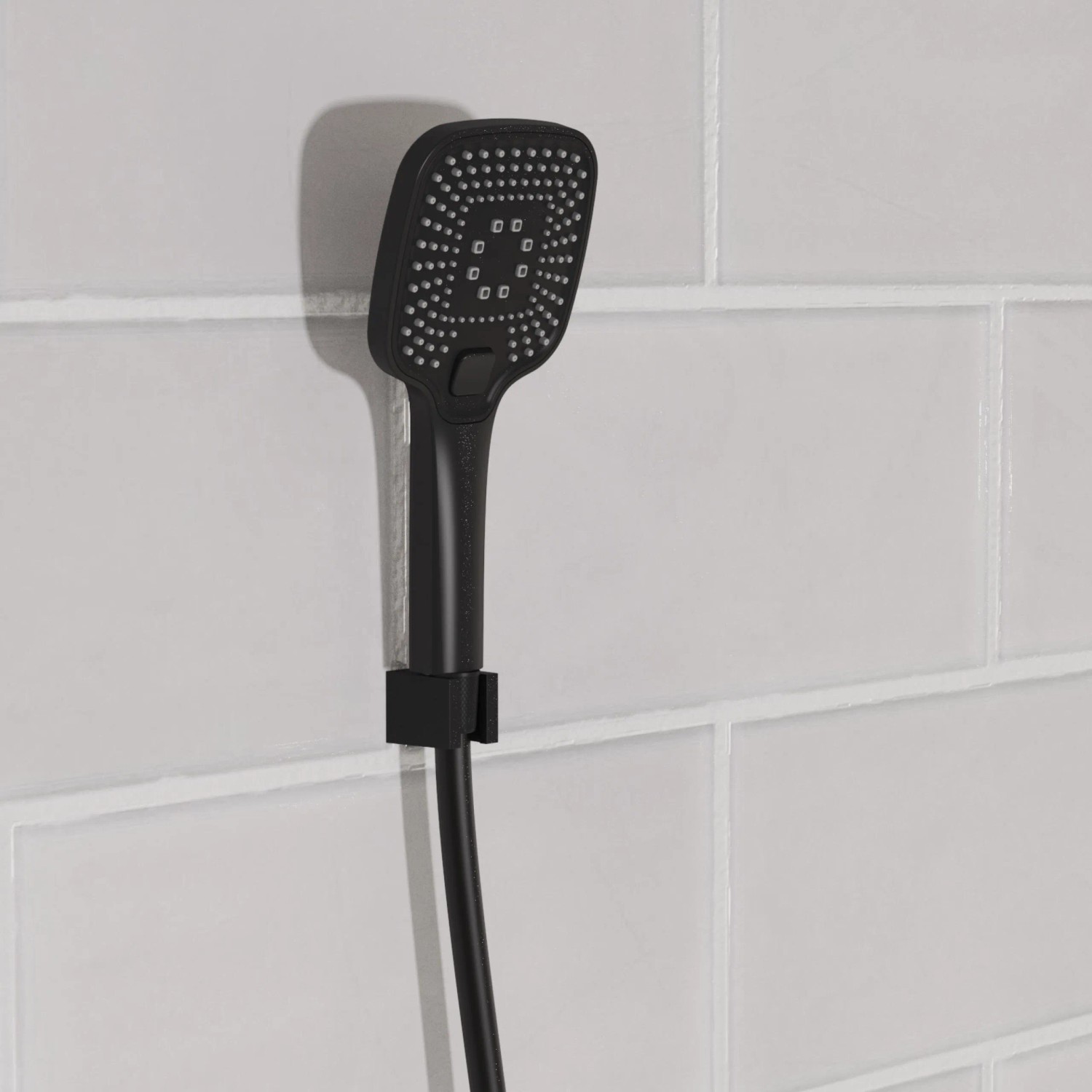 Schwarze, matte Schütte Handbrause Ravenna mit Antikalk-Noppen an weißer Wand.