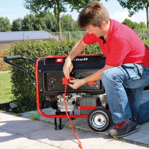 Einhell Stromerzeuger TC-PG 55 E5 in Nutzung: Mann schließt Kabel an Benzin Generator an.