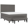 Graues Boxspringbett mit Matratze, Kopfteil und Bank aus Kunstleder.