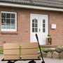 Schwarzer Relaxdays Handwagen aus Stahl mit offener Plattform, beladen mit braunen Kartons, vor einem Ziegelhaus. Ideal für Lastentransport.