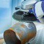 LUX Fiberscheibe im Einsatz: Winkelschleifer beim Entrosten eines Metallrohrs.