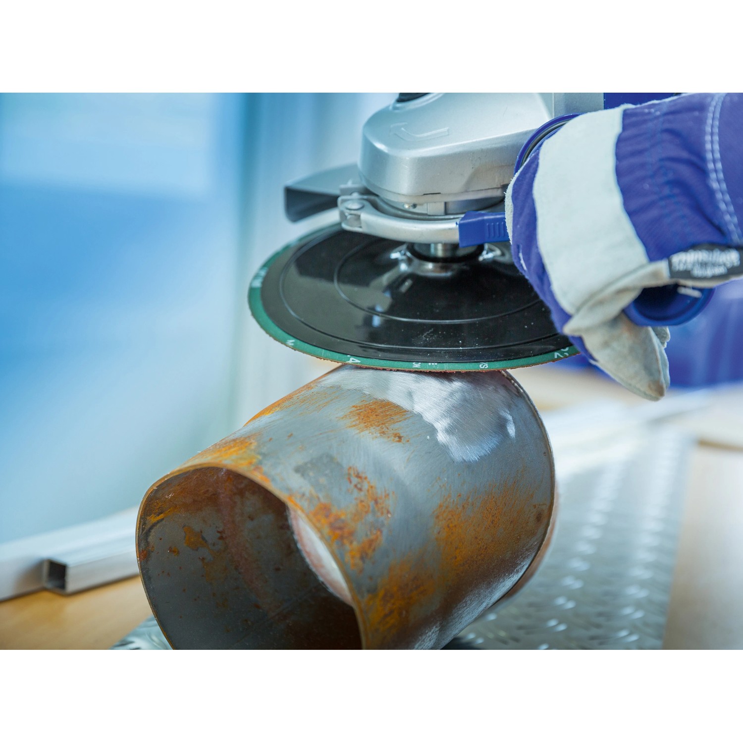 LUX Fiberscheibe im Einsatz: Winkelschleifer beim Entrosten eines Metallrohrs.
