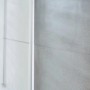 Tesa Powerstrips Haken Waterproof Zoom Edelstahl Small, 2er-Pack, an grauer Wand neben Dusche.