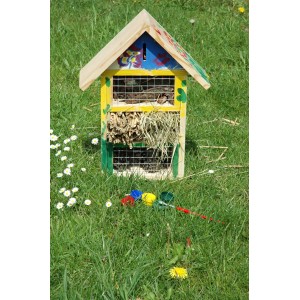 Bemaltes Dobar Insektenhotel 4-fach, 34x12x45cm, mit Farben und Pinsel auf einer Wiese.