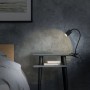 Schwarze Briloner LED-Klemmleuchte FLEKS auf Nachttisch mit warmweißem Licht.