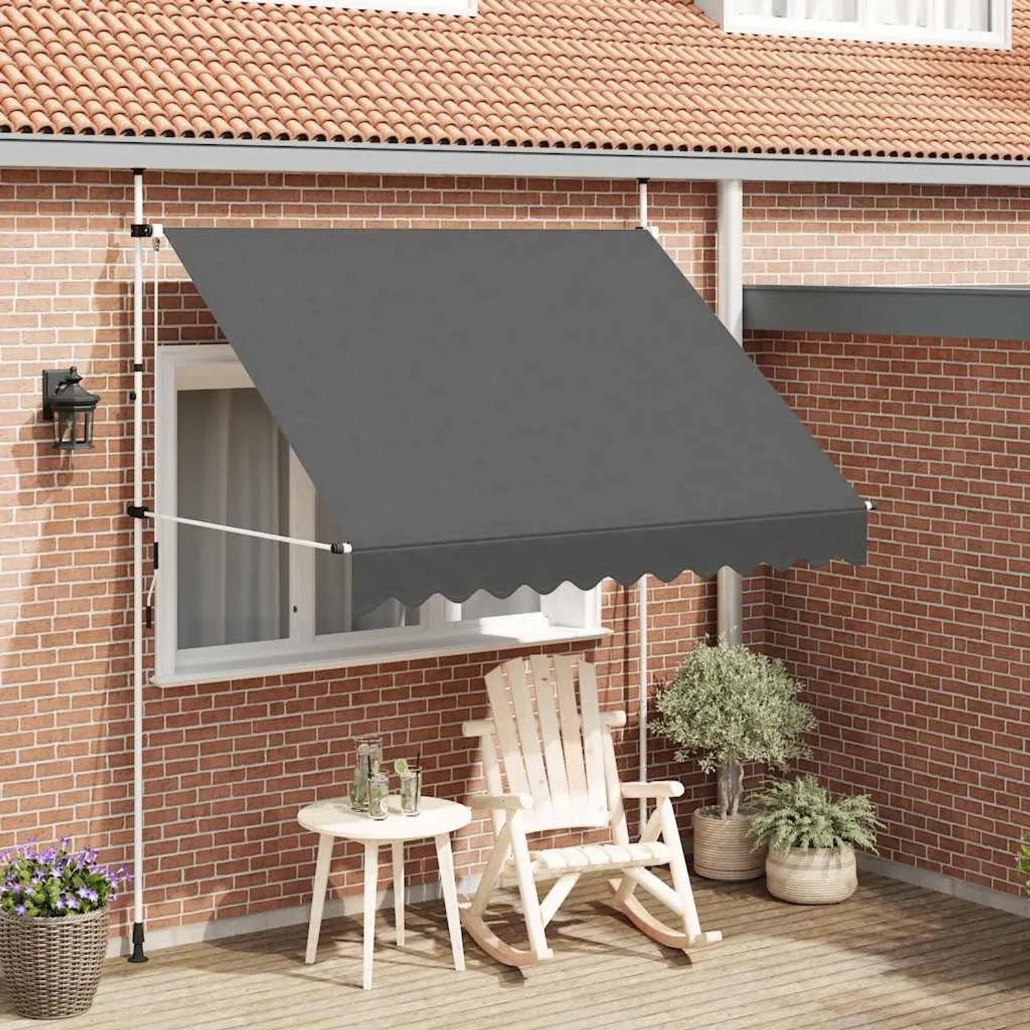 Anthrazitfarbene, handbetriebene Markise (250 cm) vor einer Hauswand mit Gartenmöbeln.