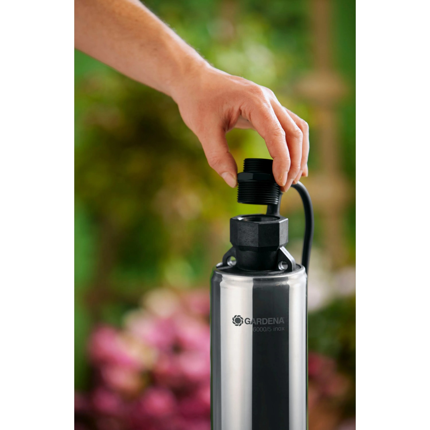 Gardena Premium Tiefbrunnenpumpe 6000/5 inox mit Hand beim Anschließen, Edelstahlgehäuse.
