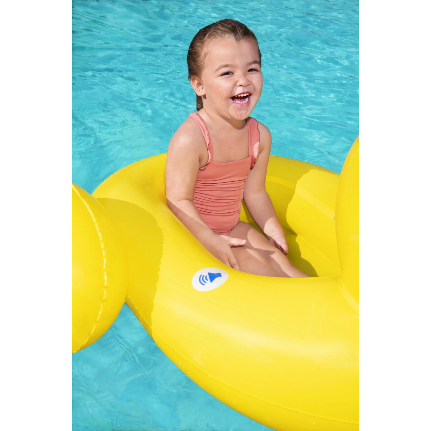 Fröhliches Kind im gelben Bestway Enten-Schlauchboot mit Lautsprecher im Pool.
