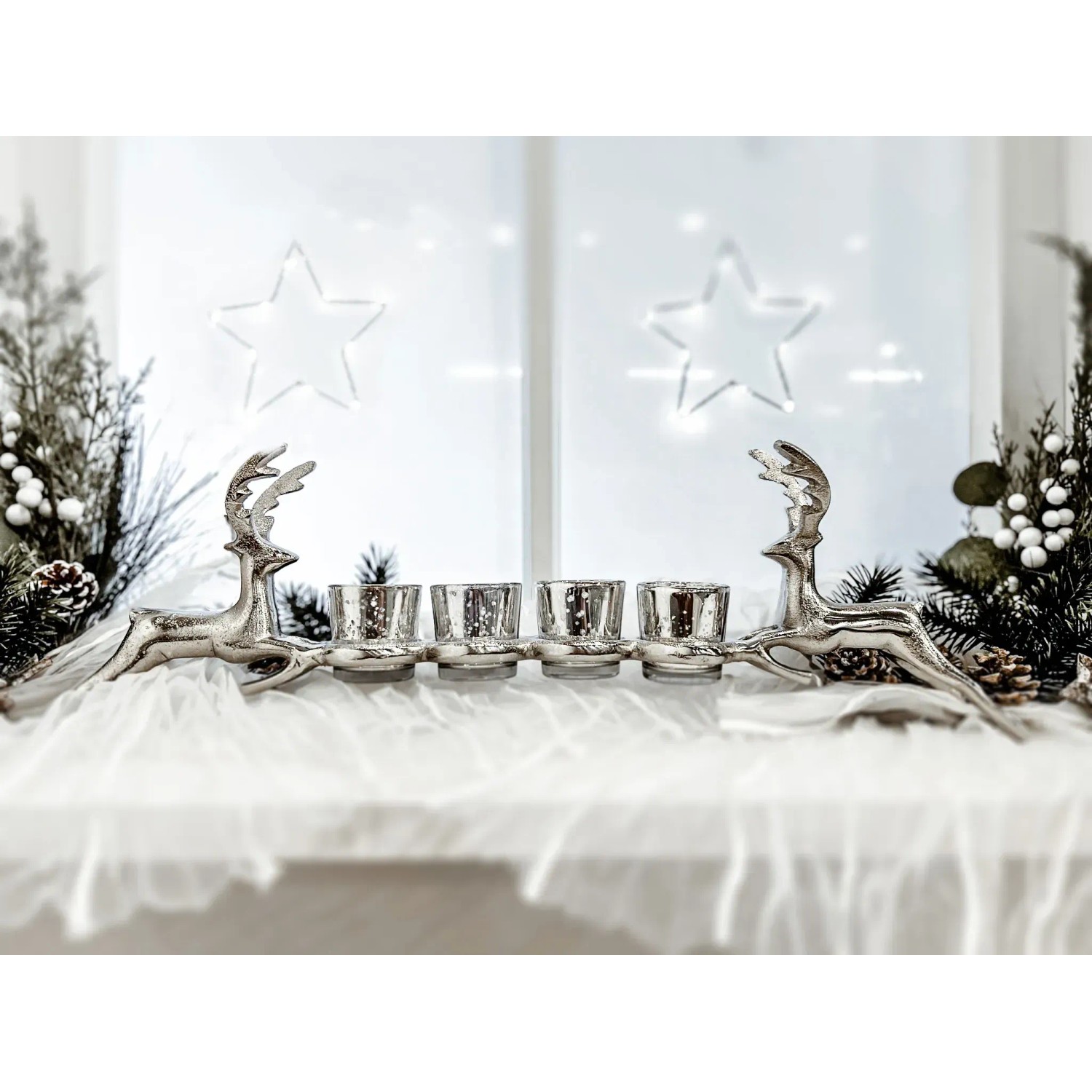 Weihnachtlicher Kerzenhalter mit zwei silbernen Rentieren und vier Teelichtern.