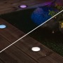 Paulmann Plug & Shine LED-Bodeneinbauleuchte RGBW auf Holzterrasse und Rasen mit farbiger Beleuchtung.