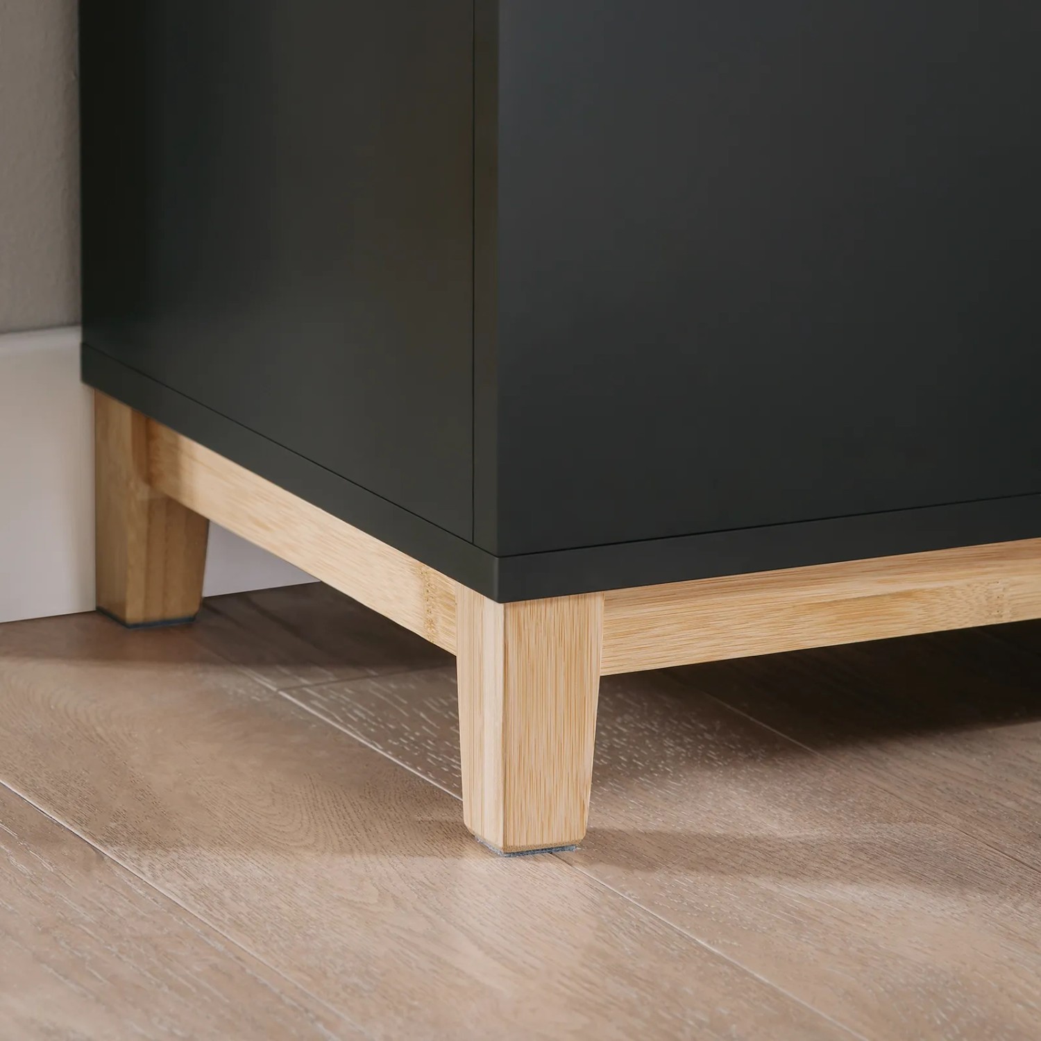 Detailaufnahme: Schwarze Schuhbank mit Sitzfläche und hellen Holzfüßen.