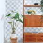 ESTAhome Tapete mit blauem Karomuster an einer Wand. Modernes Interieur mit Pflanze und Holzregal.