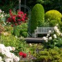 Dunkelgrüner Rosenbogen aus Eisen mit Tor als Rankhilfe im Garten. Dekorativ für Kletterpflanzen.