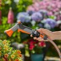 Gardena AquaCount Bewässerungsbrause in Nutzung, mit digitaler Anzeige und orangefarbenem Sprühkopf.