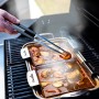 Char-Broil Spitzzange hält Garnele über Grillpfanne. Grillutensil für feines Grillgut.