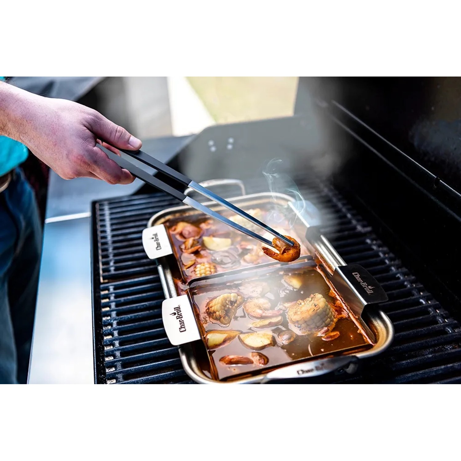 Char-Broil Spitzzange hält Garnele über Grillpfanne. Grillutensil für feines Grillgut.