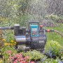 Gardena Haus- und Gartenautomat 6000/6 LCD Inox im Einsatz, umgeben von Blumen und Wasser.