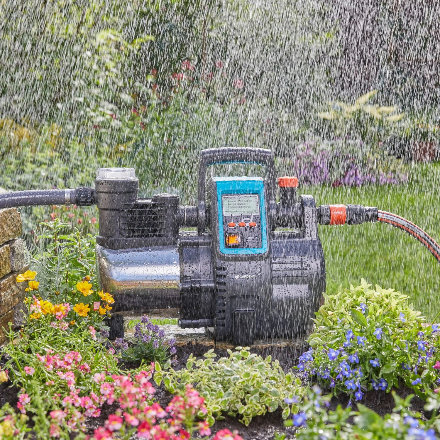 Gardena Haus- und Gartenautomat 6000/6 LCD Inox im Einsatz, umgeben von Blumen und Wasser.