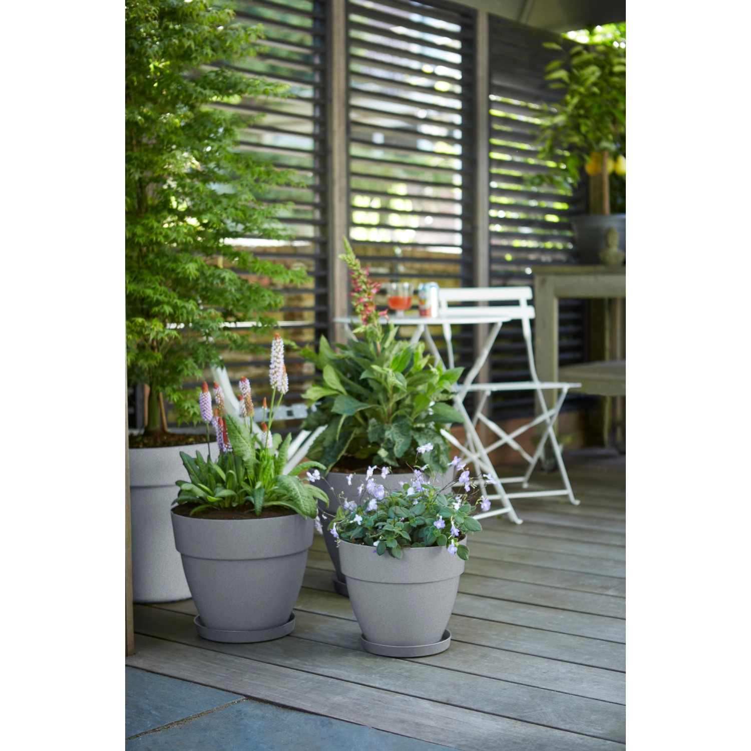 Elho Blumentopf Vibia Campana, Ø 20 cm, Living Beton, mit Pflanzen auf einer Terrasse.