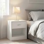 Weißer Relaxdays Nachttisch aus MDF mit einer Schublade und offenem Fach, neben einem Bett mit Lampe.