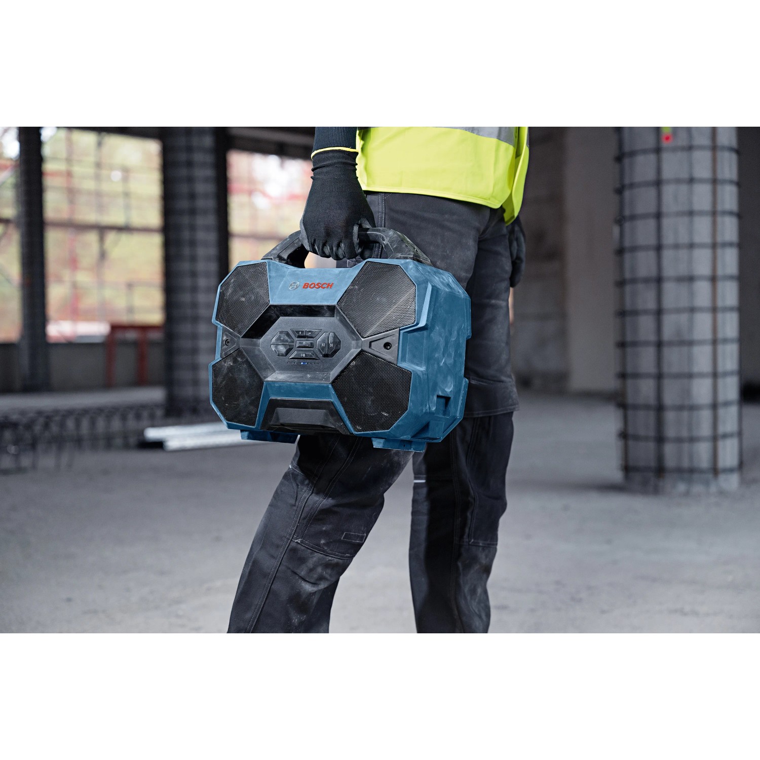 Bosch Professional Bluetooth-Lautsprecher GPB 18V-6C, getragen von einer Person auf einer Baustelle.