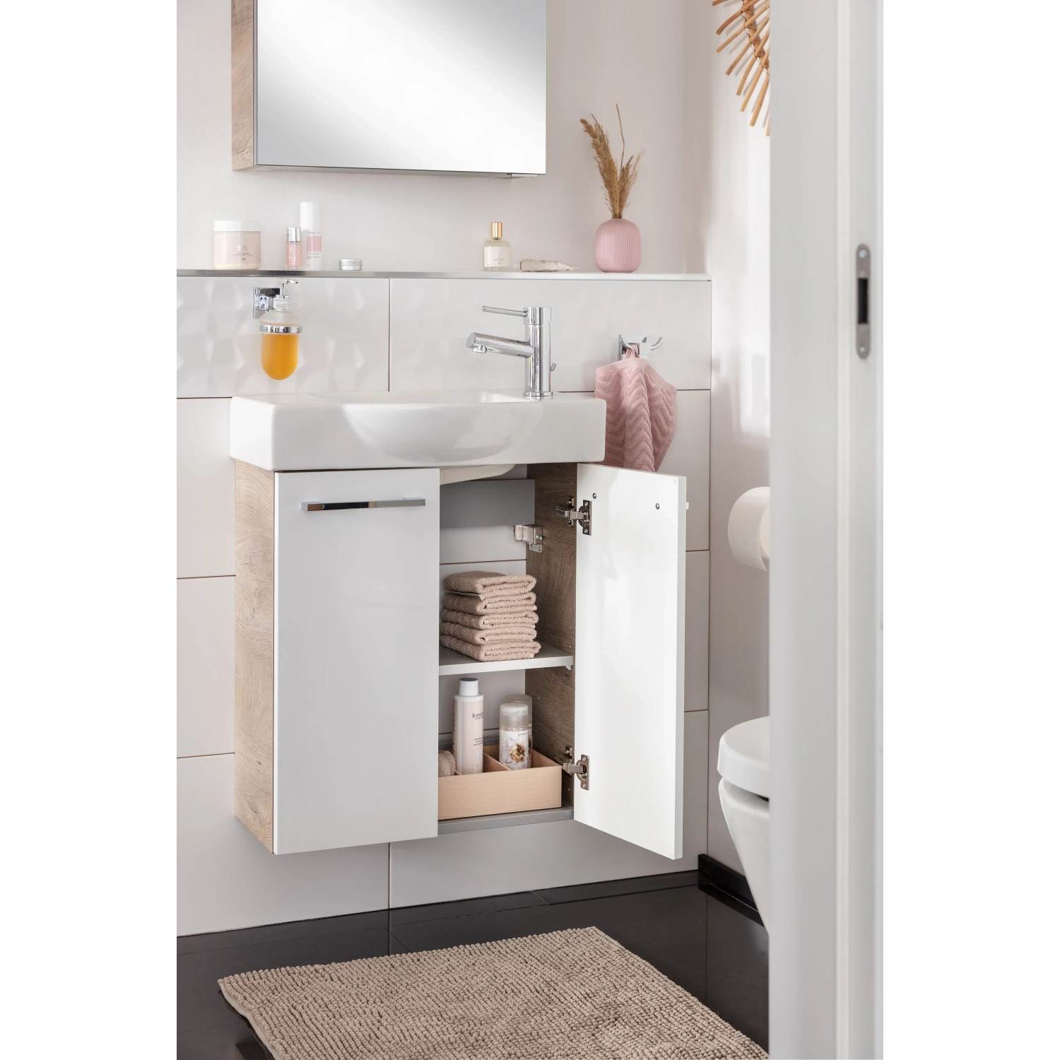 Fackelmann Waschbeckenunterschrank SBC Eiche Natur, 52 cm breit, mit geöffneter Tür und Badutensilien.