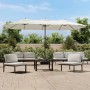 Großer sandweißer Doppel-Sonnenschirm mit LED-Leuchten auf einer Terrasse. Bietet Schatten für Gartenmöbel.