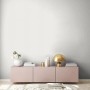 Wohnraum mit weißer Vliestapete Uni Metallic, rosa Sideboard und Deko.