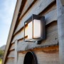 Moderne Lutec LED Solar-Wandleuchte Curtis mit Bewegungsmelder an einer Holzwand.