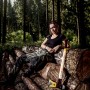 Halder Spaltaxt Simplex mit Keilstegen und Hickorystiel, neben einer Frau auf Baumstämmen im Wald.