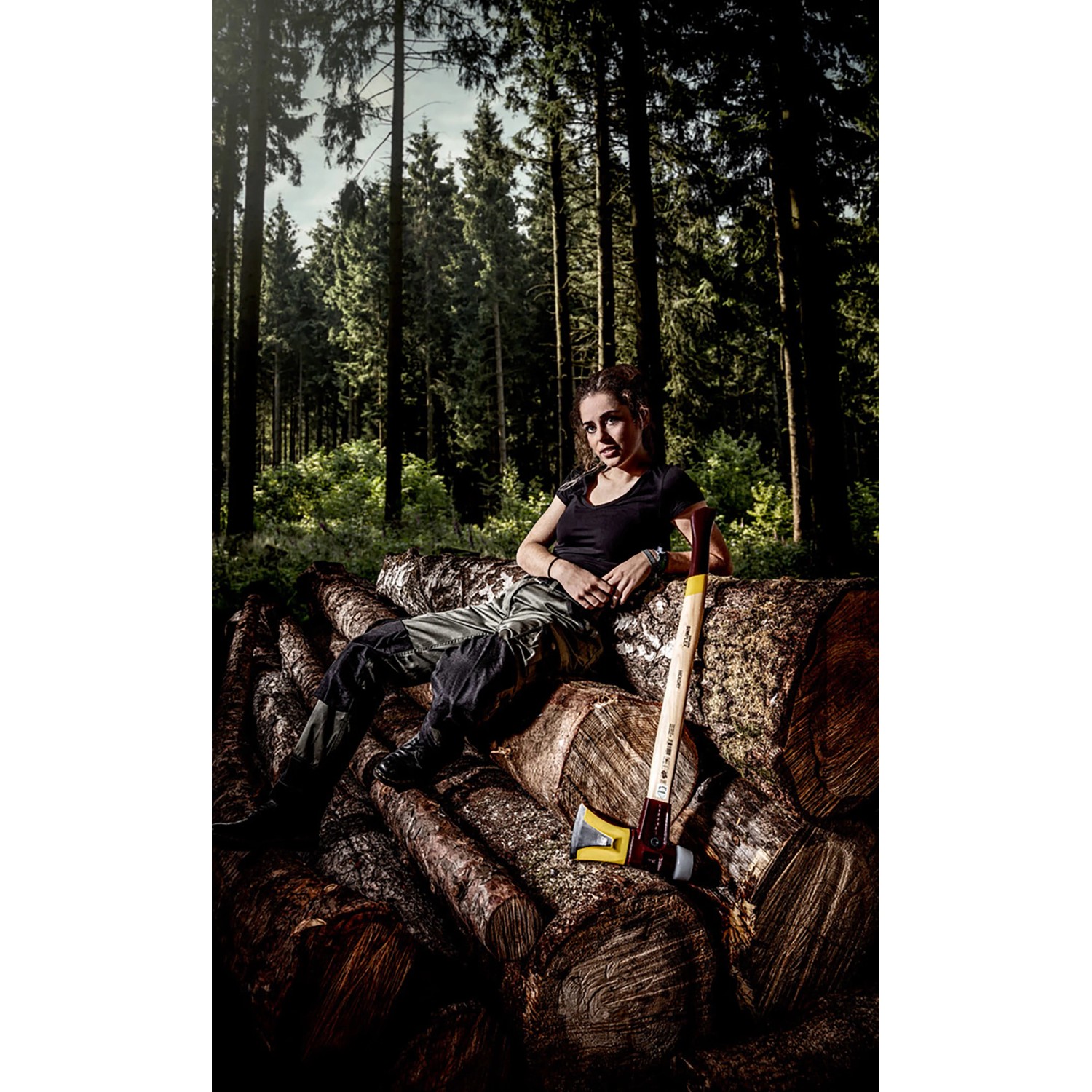 Halder Spaltaxt Simplex mit Keilstegen und Hickorystiel, neben einer Frau auf Baumstämmen im Wald.