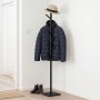 Schwarzer Garderobenständer in Baumform aus Holz mit 8 höhenverstellbaren Haken. Eine Jacke und ein Hut hängen daran im Flur.
