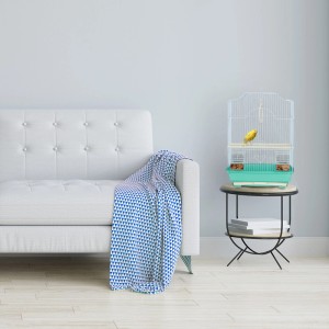 Mintgrüner Relaxdays Vogelkäfig mit gelbem Kanarienvogel auf Tisch neben Sofa.