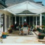 Floracord Sonnensegel-Bausatz, elfenbeinfarben, 420x140cm, montiert über einer Terrasse mit Tisch und Stühlen.