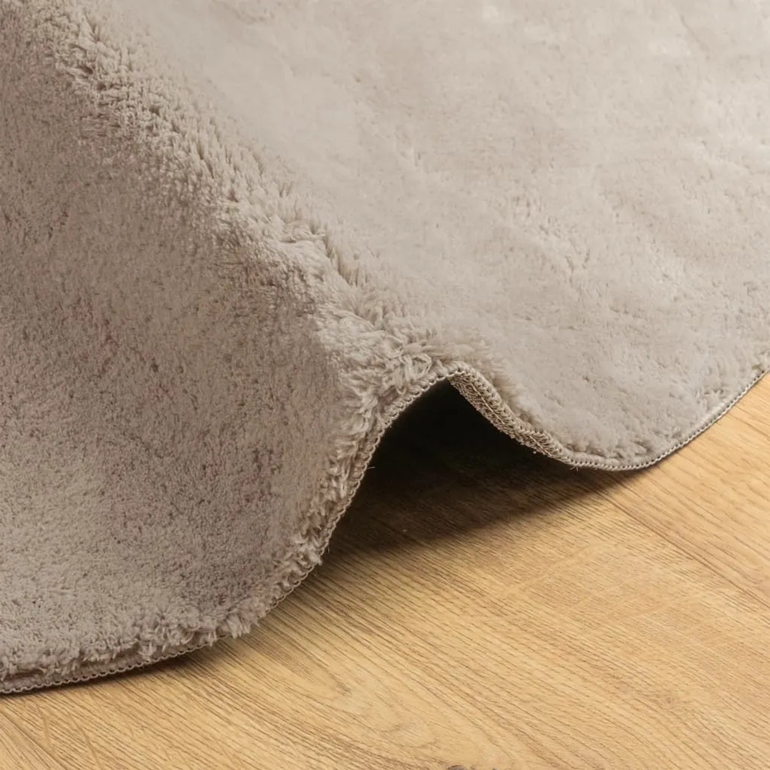 Sandfarbener, weicher Kurzflor-Teppich HUARTE, Ø 80 cm, aus Polyester, auf hellem Holzboden.