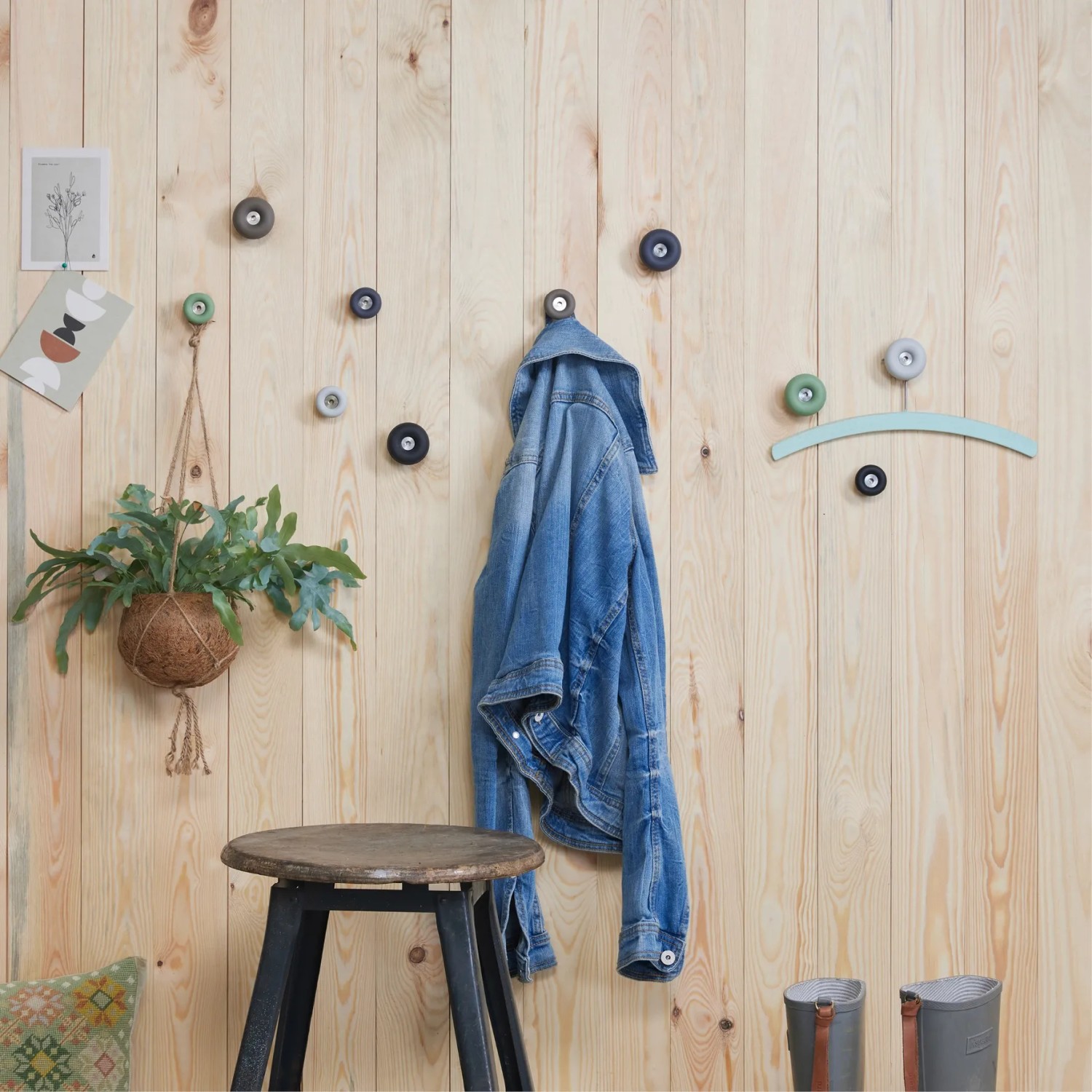 Wand mit mehreren hellgrauen Wagner Wandhaken Hooks4home Dot, einer Jacke und Deko.