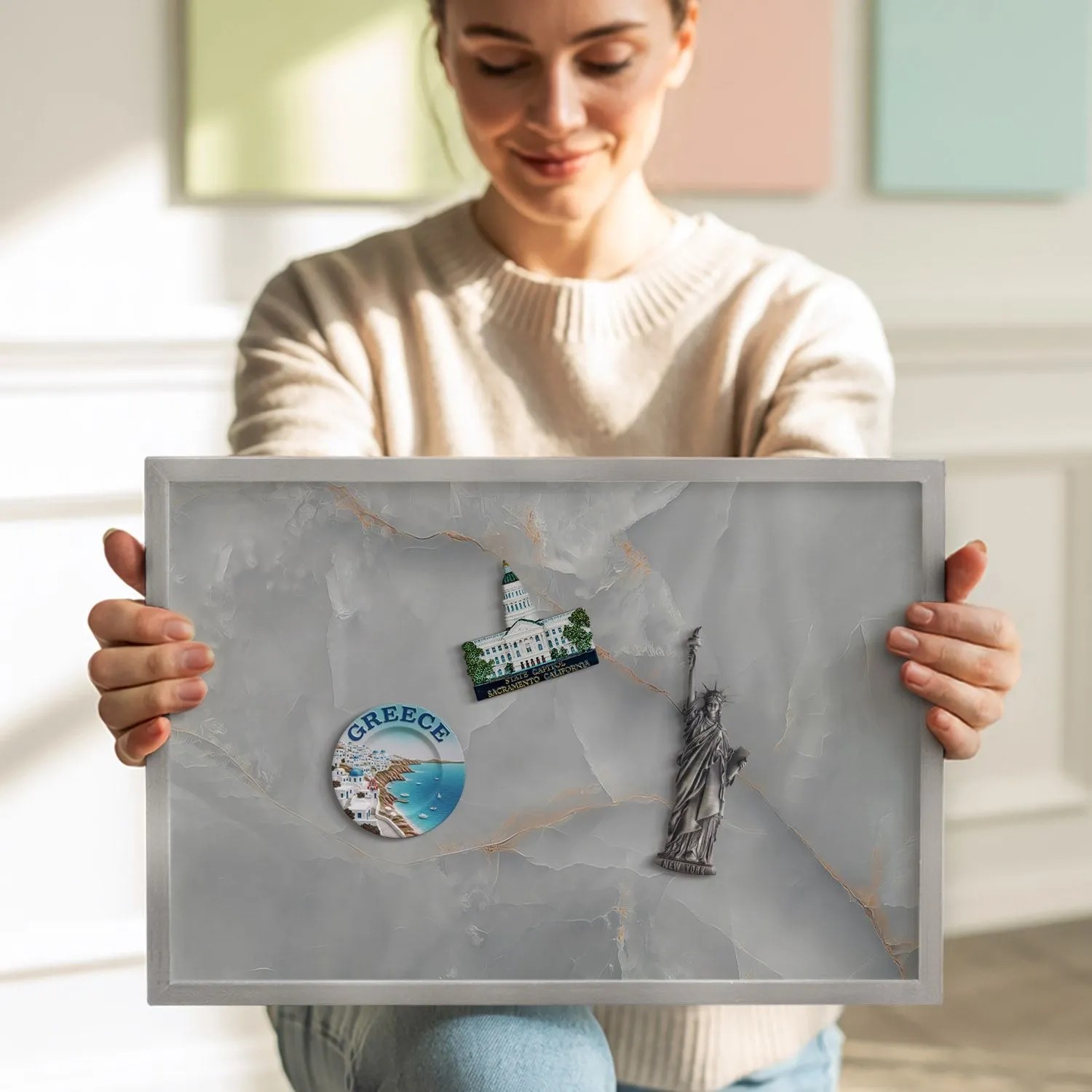 Magnettafel mit Marmor-Design und silbernem Rahmen, gehalten von einer Person. Pinnwand für Notizen und Magnete.