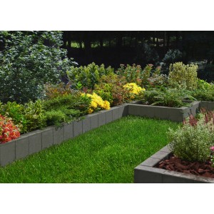 Anthrazitfarbener Rechteck Palisadenrandstein als Beeteinfassung im Garten.