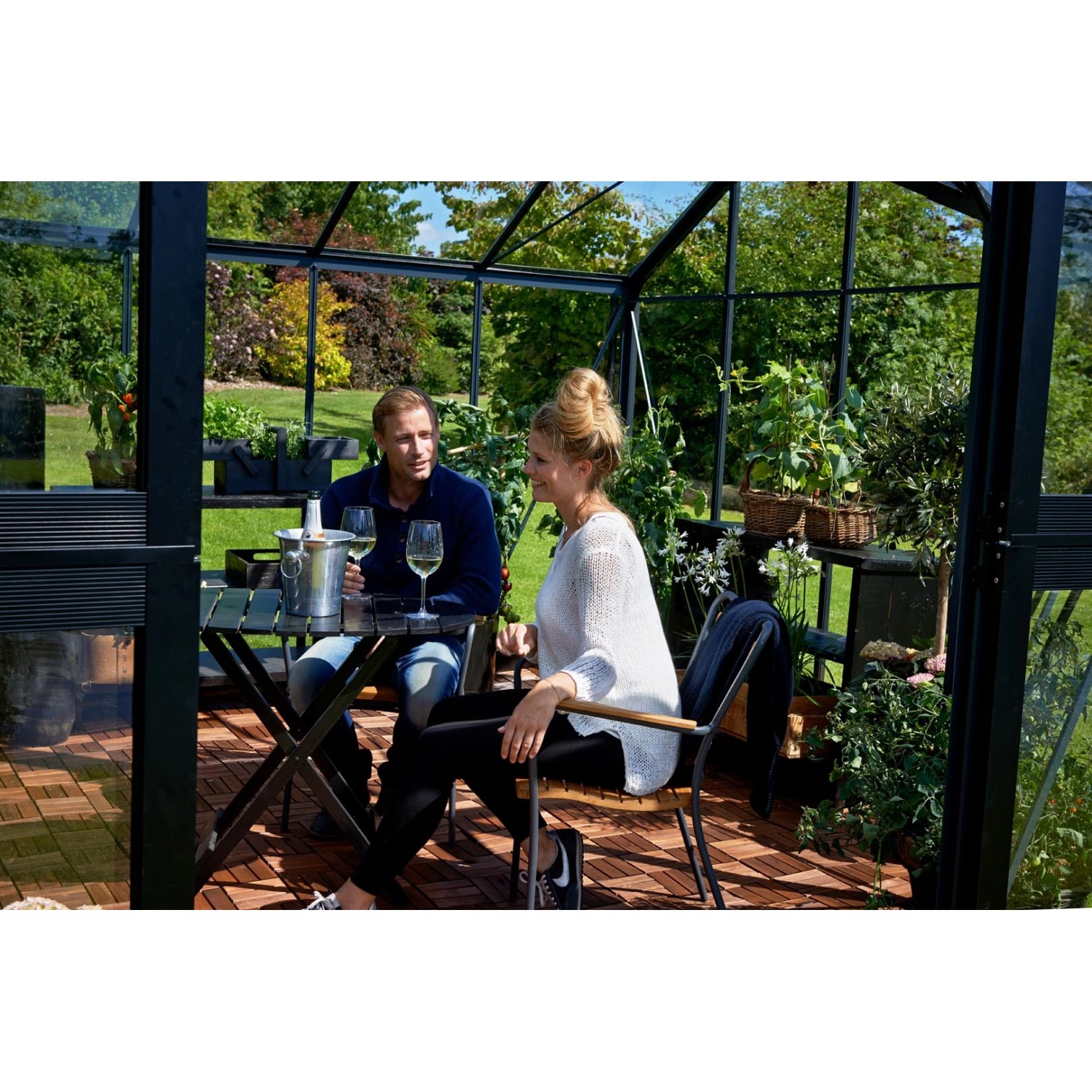 Juliana Gewächshaus Orangerie 15: Paar entspannt mit Wein im schwarz-anthrazitfarbenen Gewächshaus.