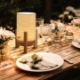 Näve LED-Tischleuchte Madita mit Leinen-Schirm und Holzfuß auf gedecktem Tisch.