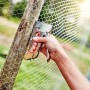 Rapid Handtacker R153 beim Befestigen von Drahtgeflecht an einem Holzpfosten.