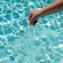 Bayrol QuickTest: Hand taucht Teststreifen zur Poolwasseranalyse ins Wasser.