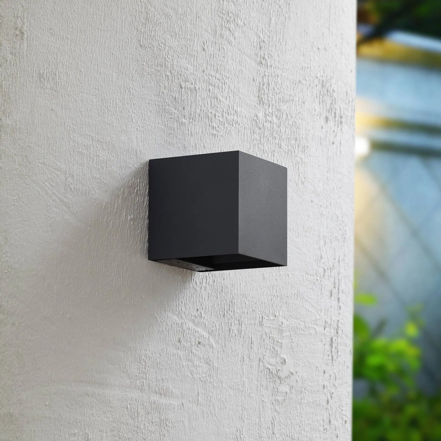 Moderne, schwarze PRIOS LED Außenwandleuchte Lius mit Bewegungsmelder an weißer Wand.