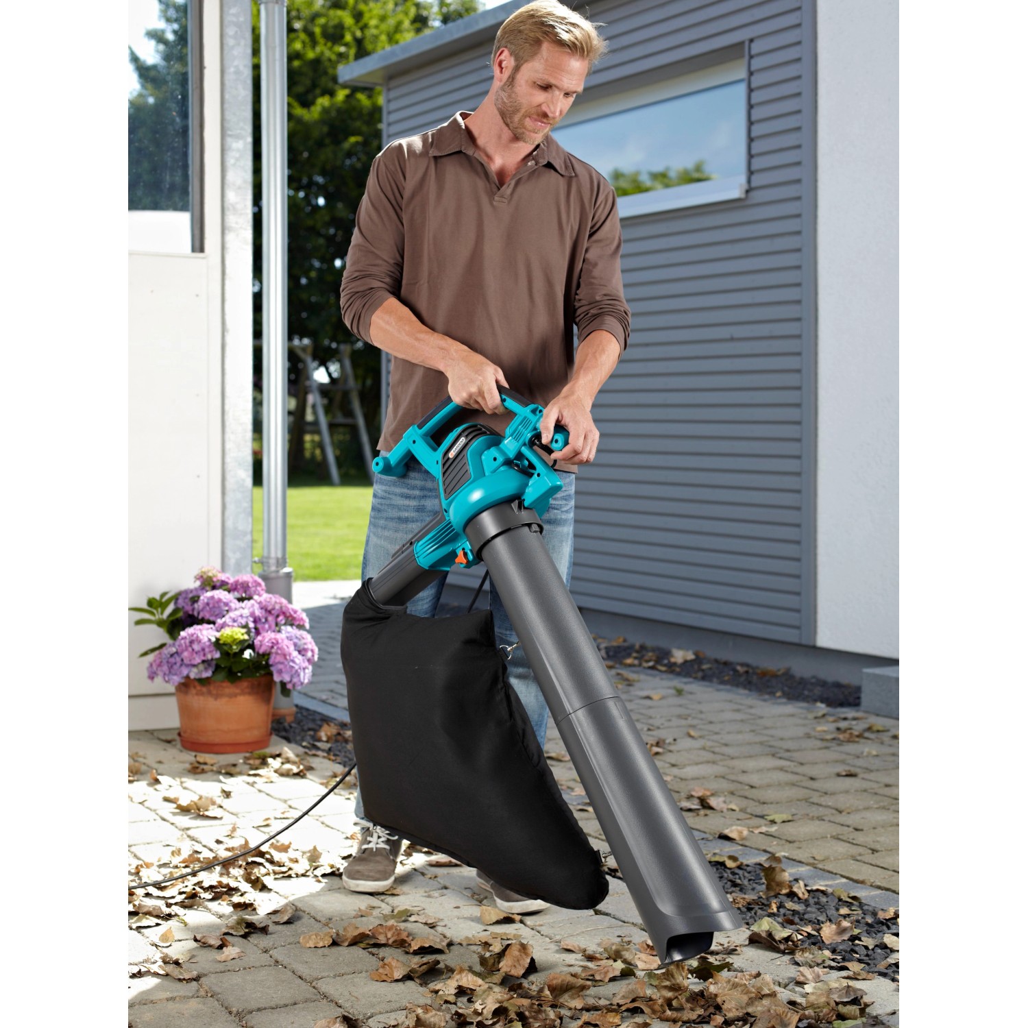 Mann benutzt Gardena Elektro-Laubbläser ErgoJet 3000 zum Laubsaugen im Garten.