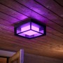 Quadratische Philips Hue Econic LED-Wandleuchte mit Farbwechsel, montiert an einer Holzdecke.