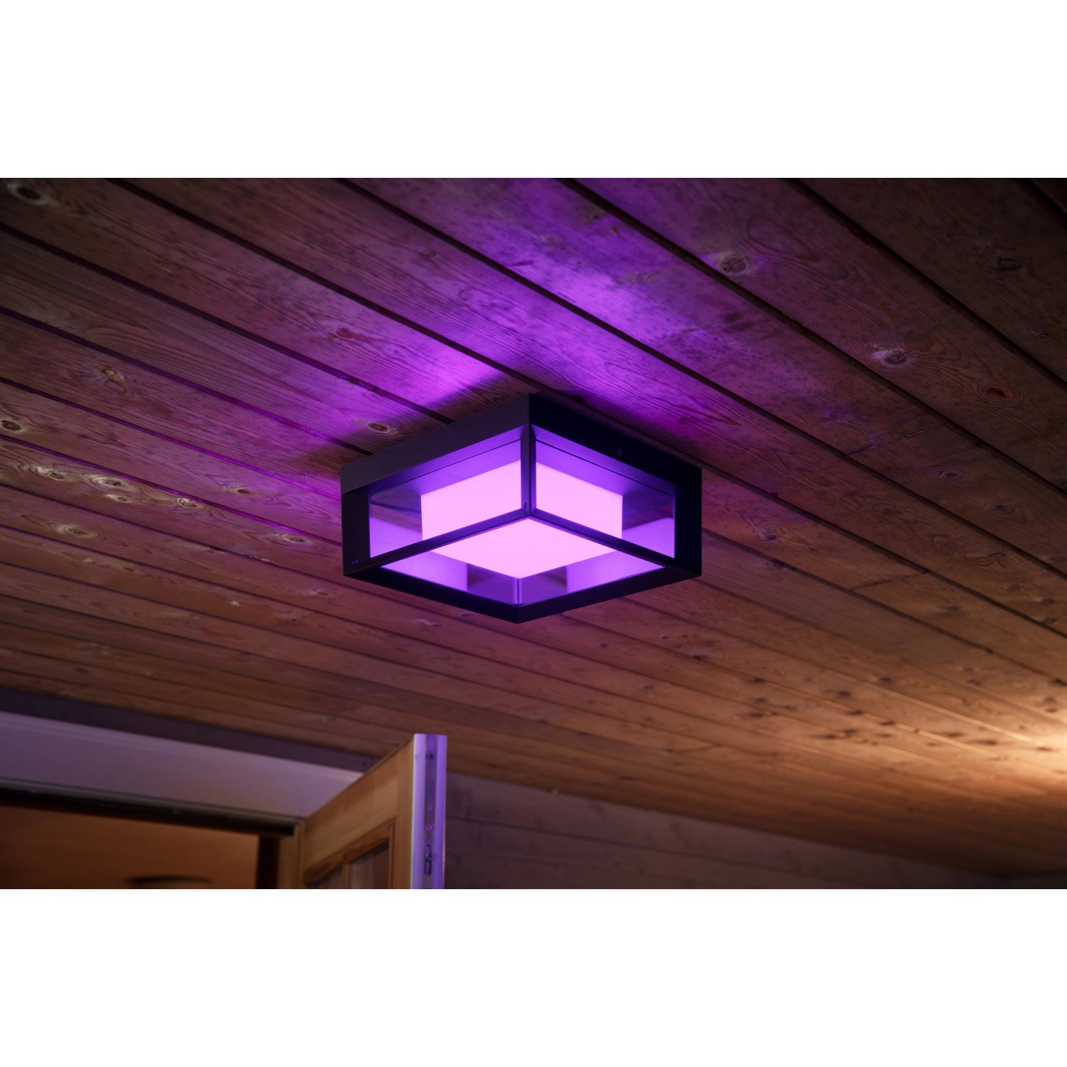 Quadratische Philips Hue Econic LED-Wandleuchte mit Farbwechsel, montiert an einer Holzdecke.