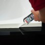 Hand verfugt mit Soudal Fix All Flexi Dichtstoff eine Fuge zwischen weißer Wanne und schwarzer Fläche.